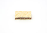 A Single piece of Chewy Praline Fudge.  The Fudge has a layer of caramel and pecans in the middle, the top is lightly swirled with Caramel.