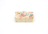 A single piece of Birthday Cake Fudge.  The Fudge is a creamy white topped with Birthday Sprinkles. 